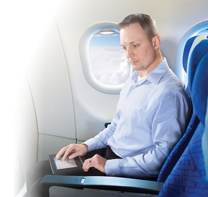 Picture of a man using the BrailleNote Touch while travelling on a plane