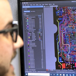 Photo of a hardware design intern in front of his screen working on the development of a computer circuit for one of our devices.