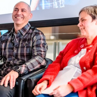 Photo of two HumanWare employees sitting side by side smiling during an annual training day.