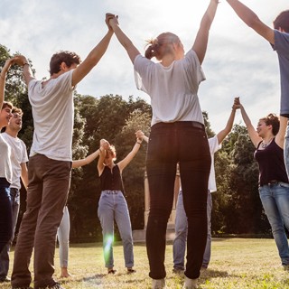 Photo of a group of employees outside holding their hands to the sky.