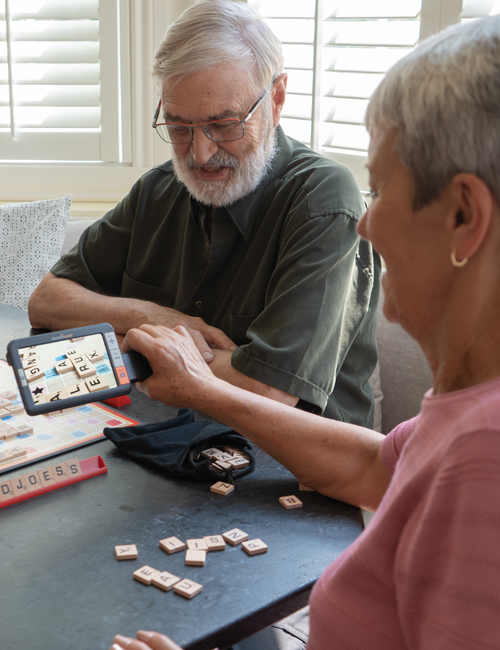 Image de deux personnes jouant au Scrabble ; l'une d'elles utilise l'exploré 5 pour agrandir les tuiles du plateau et des lettres.