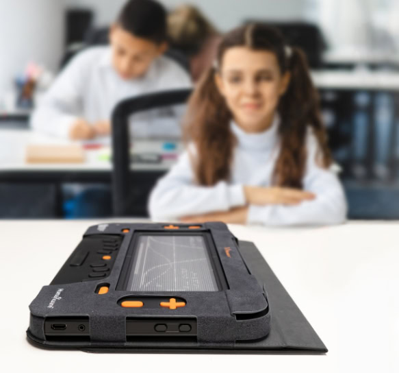 A student sits in a classroom in front of a Monarch refreshable tablet, while a screen behind the device displays a mathematical graph.