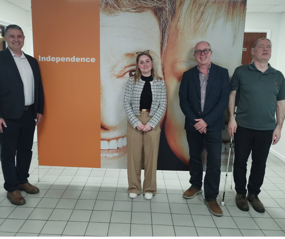 Chris, Gen, Alan & Martin standing in HumanWare's reception area in front of a large poster saying "Independence".