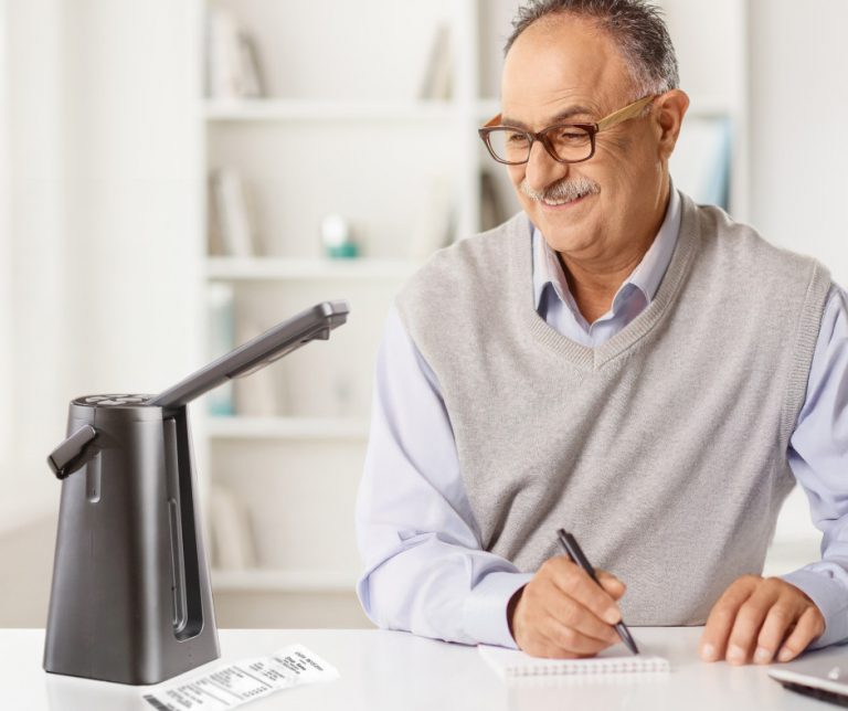 Image of a smiling, mature man taking notes in front of a laptop, the Odyssey captures the text on an invoice.