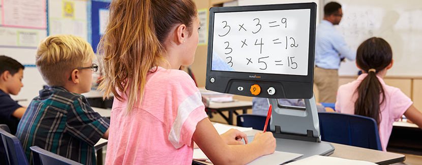 Image of a schoolgirl in class using Reveal 16 to enlarge a mathematical problem presented on the whiteboard at the front of the classroom.