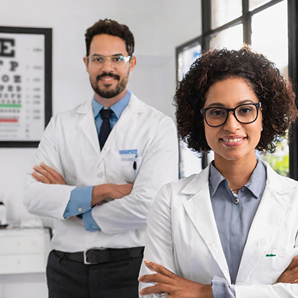 Image of two smiling optometrists. In the background, an eye chart hangs on the wall.