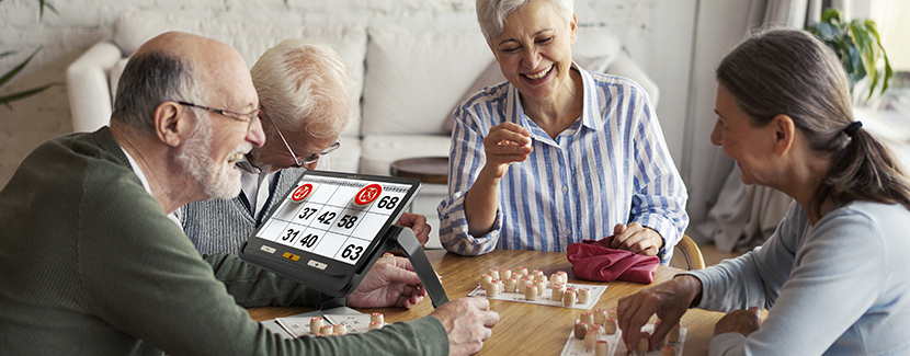 Image of seniors playing bingo with one of the people using the explore 12 electronic magnifyer to see the numbers more clearly during the game.