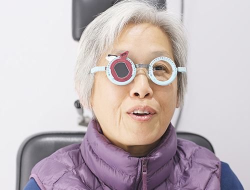 Image of an Elderly woman taking a visual acuity test with a smile on her face.