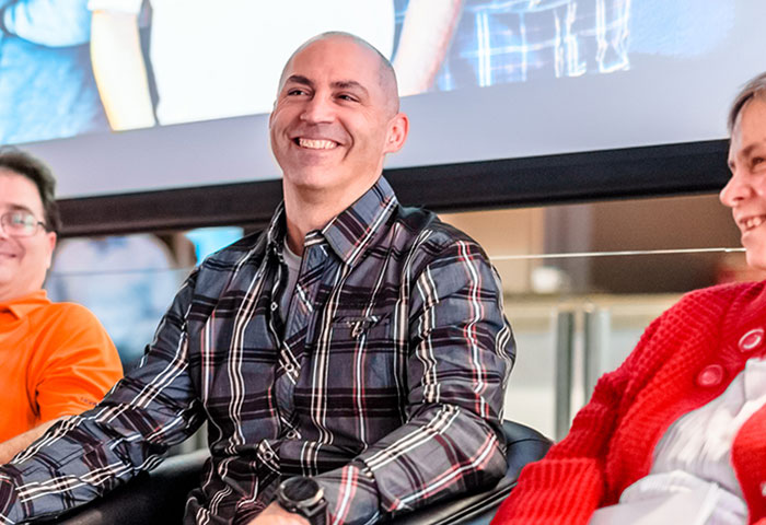 HumanWare employees sitting side by side smiling during an annual training day.