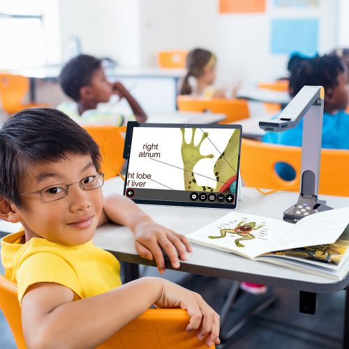 Image of a classroom with a student using a digital tablet connected to the camera to enlarge a book on the biology of a frog.